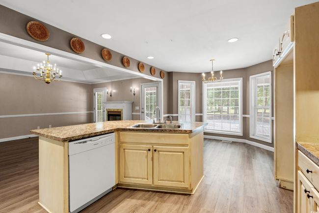 Kitchen with dishwasher, a chandelier, light brown cabinetry, a glass covered fireplace, and recessed lighting | Image 30