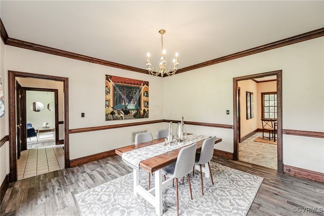 Dining space with a chandelier, wood finished floors, crown molding, and baseboards | Image 24