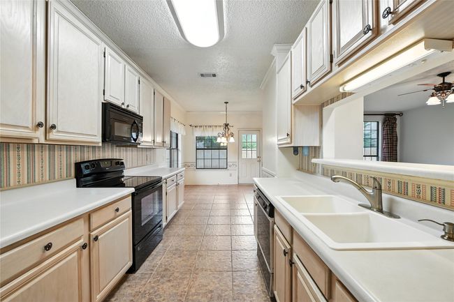 Kitchen with black appliances, a textured ceiling, light countertops, and ceiling fan | Image 15
