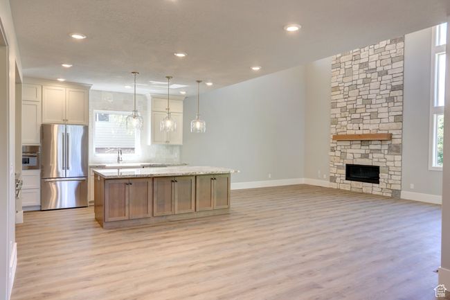 Kitchen featuring freestanding refrigerator, light wood-style flooring, decorative backsplash, a center island, and open floor plan | Image 4