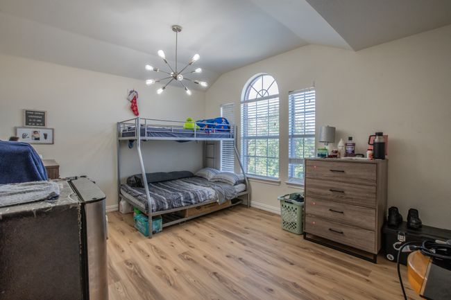 Bedroom with baseboards, lofted ceiling, a chandelier, and light wood-type flooring | Image 15