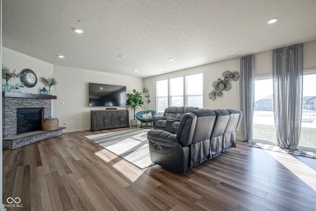 living area with a textured ceiling, wood finished floors, recessed lighting, and a stone fireplace | Image 13