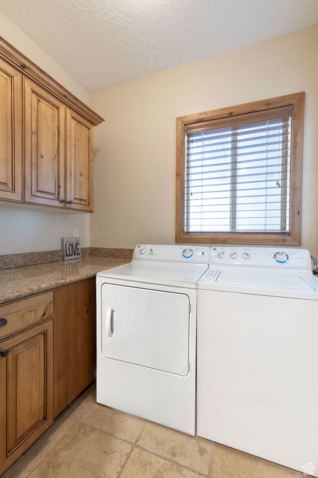 Clothes washing area featuring cabinet space, washing machine and dryer, and a textured ceiling | Image 33