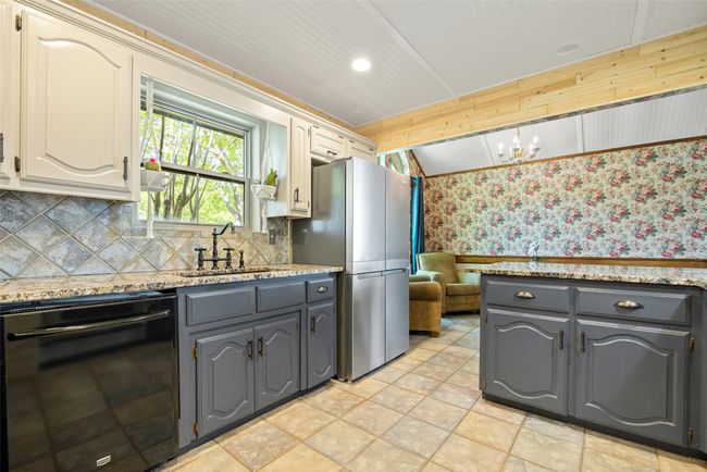 Kitchen with freestanding refrigerator, dishwasher, a sink, wallpapered walls, and gray cabinetry | Image 10