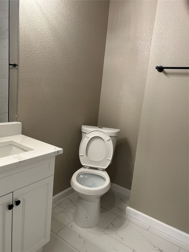 Half bathroom featuring marble look tile flooring, vanity, toilet, and baseboards | Image 24
