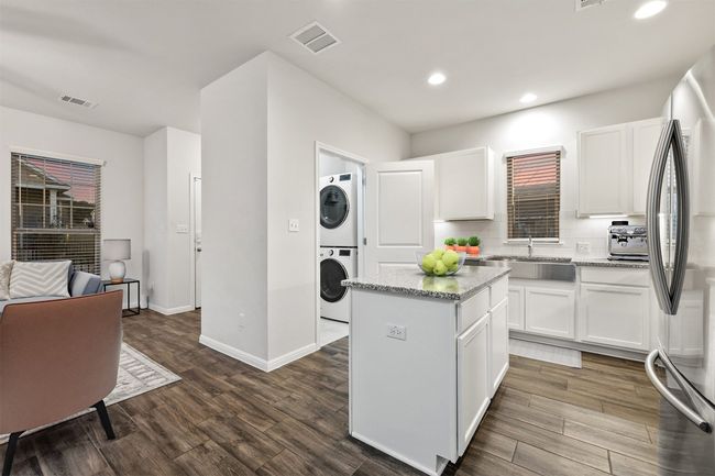 Kitchen featuring tasteful backsplash, dark wood-style flooring, freestanding refrigerator, and stacked washer / dryer | Image 7