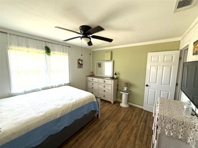 Bedroom featuring dark wood-style floors, ceiling fan, a textured ceiling, and ornamental molding | Image 23