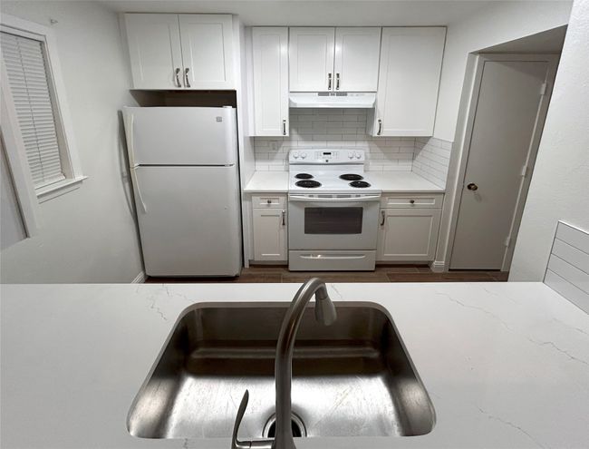 Kitchen with sink, white appliances, white cabinetry, and backsplash | Image 6