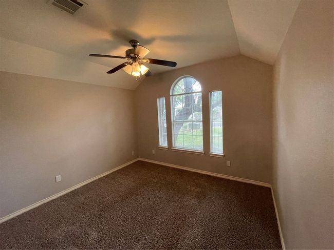 Empty room featuring lofted ceiling, dark colored carpet, and ceiling fan | Image 15
