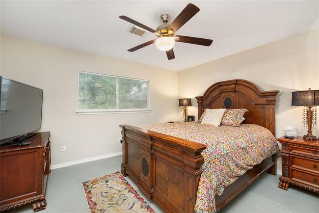 The primary bedroom offers ample space, a ceiling fan for comfort, and natural light that filters through the window—creating a calm retreat. | Image 12