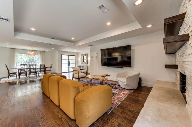 Living room with a tray ceiling, dark wood finished floors, recessed lighting, baseboards, and a fireplace | Image 10