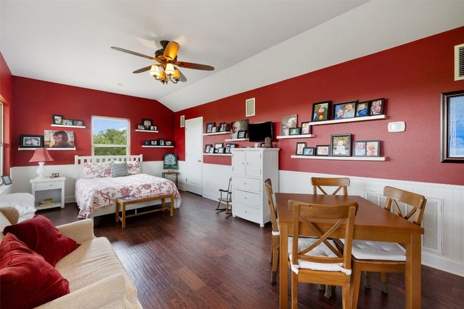 Bedroom featuring visible vents, wainscoting, wood finished floors, and lofted ceiling | Image 27