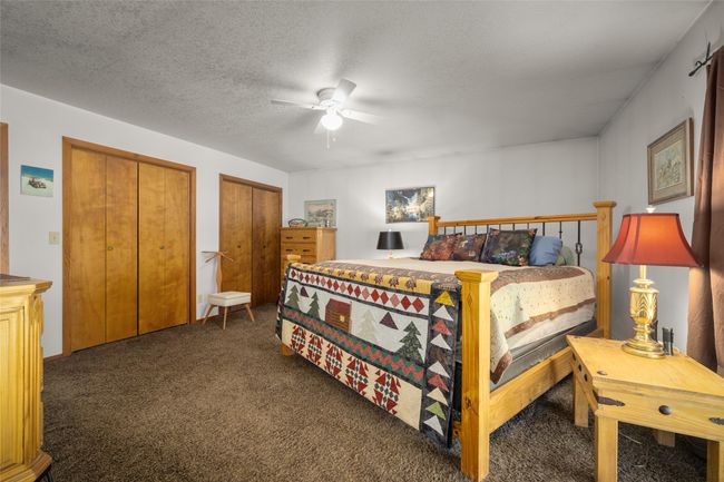 Carpeted bedroom featuring multiple closets, a ceiling fan, and a textured ceiling | Image 14