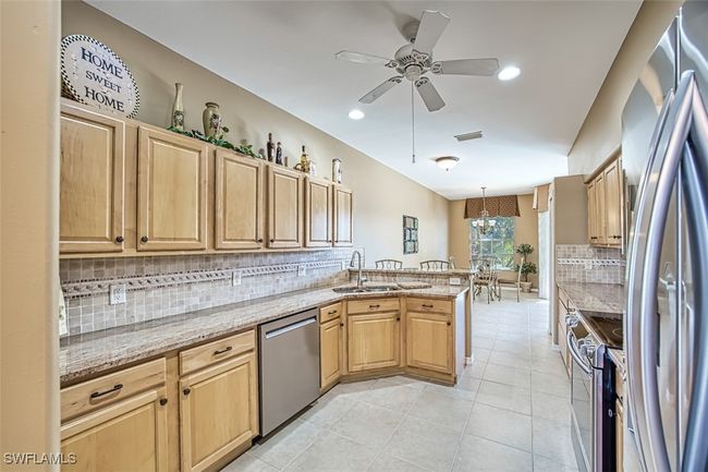 Kitchen featuring light stone countertops, sink, stainless steel appliances, backsplash, and pendant lighting | Image 22