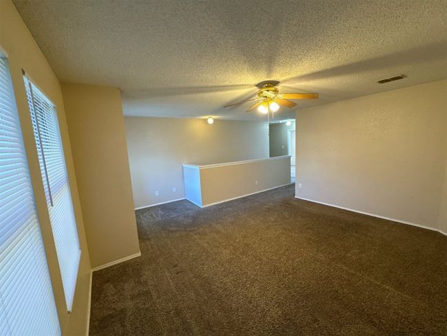 Carpeted empty room featuring ceiling fan and a textured ceiling | Image 12