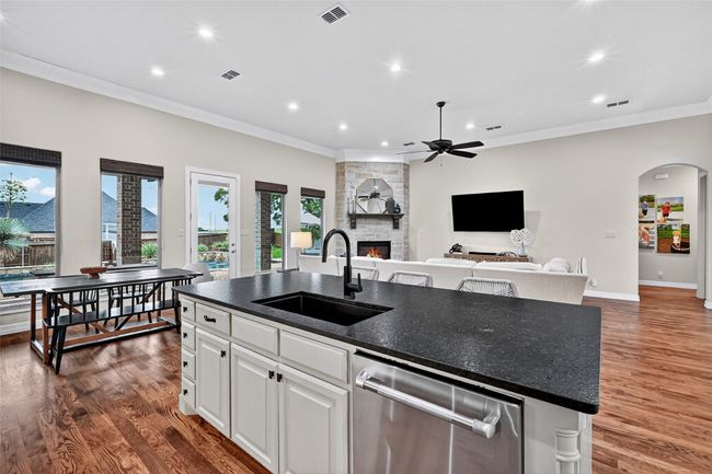 Kitchen with stainless steel dishwasher, recessed lighting, a stone fireplace, a center island with sink, and open floor plan | Image 14