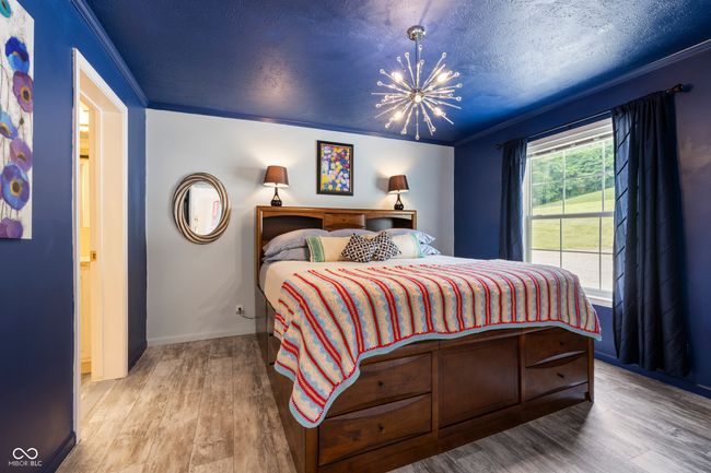 bedroom with crown molding, wood finished floors, a chandelier, and a textured ceiling | Image 20
