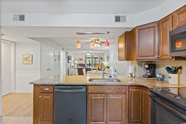 Kitchen featuring visible vents, a peninsula, ceiling fan, a sink, and appliances with stainless steel finishes | Image 7
