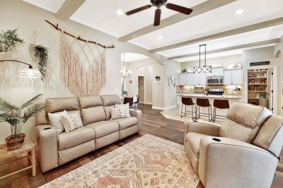 Living room with crown molding, dark hardwood / wood-style floors, beamed ceiling, and ceiling fan with notable chandelier | Image 3