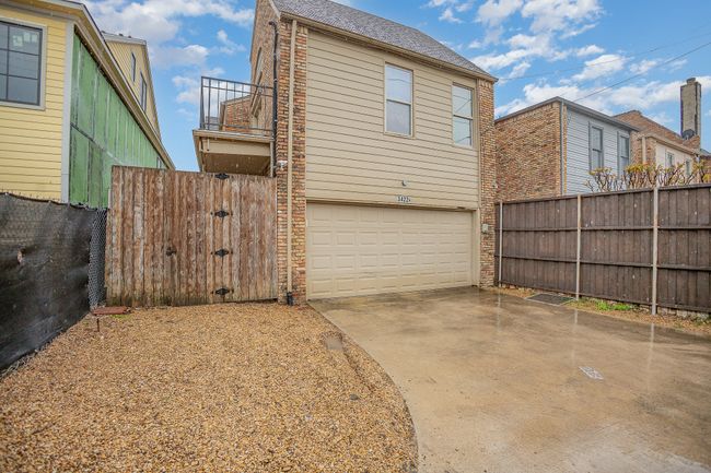 View of side of home featuring roof with shingles, a balcony, driveway, an attached garage, and fence | Image 22