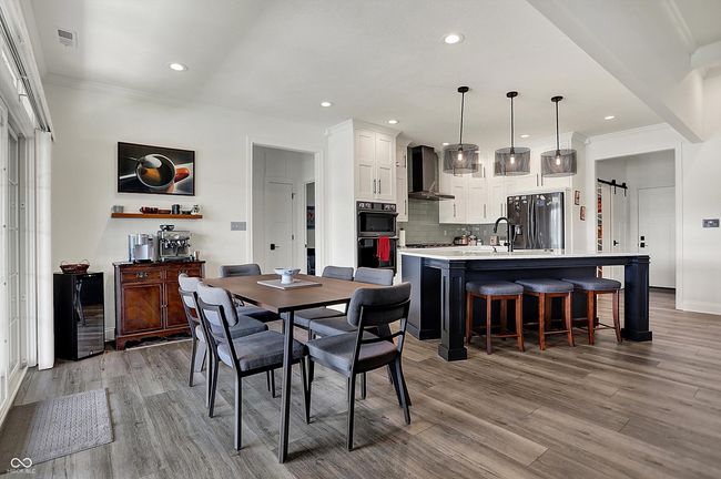 dining area with light wood-style flooring, beverage cooler, recessed lighting, and crown molding | Image 20