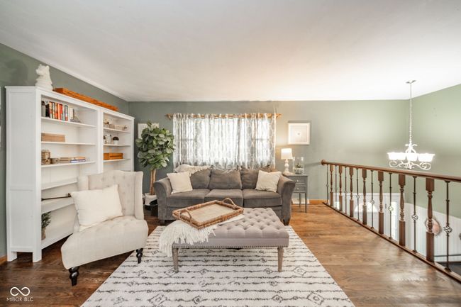 living room featuring wood finished floors, an inviting chandelier, and baseboards | Image 35