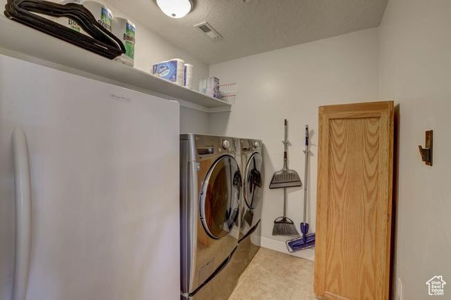 Washroom featuring washing machine and clothes dryer, light tile patterned flooring, visible vents, and laundry area | Image 25