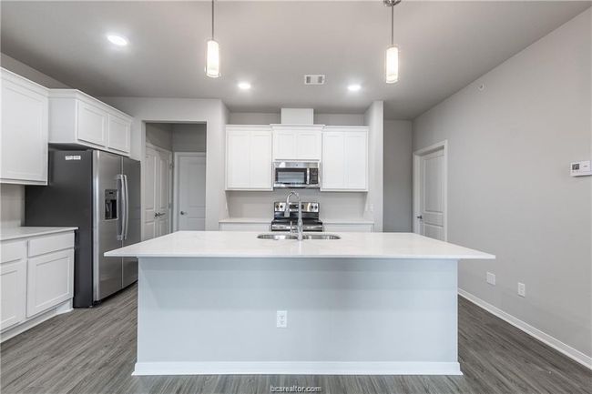 Kitchen featuring white cabinets, appliances with stainless steel finishes, and hanging light fixtures | Image 9