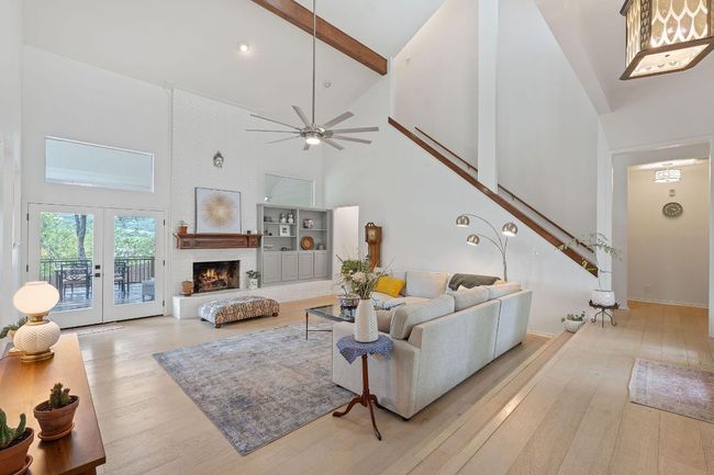 Living area with high vaulted ceiling, light wood-style floors, stairs, beamed ceiling, and a ceiling fan | Image 5