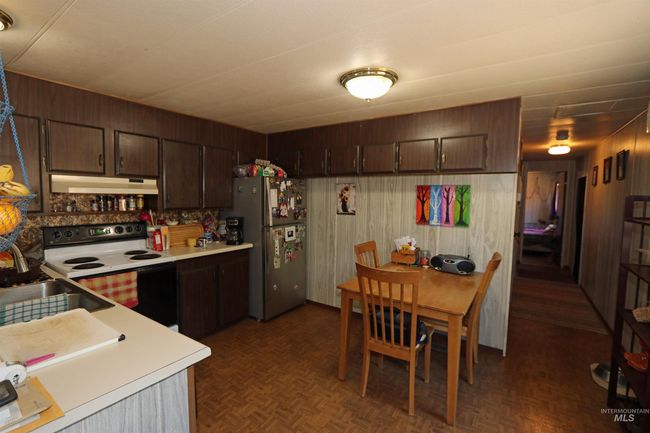 Kitchen with white range with electric cooktop, light countertops, under cabinet range hood, freestanding refrigerator, and dark brown cabinets | Image 14