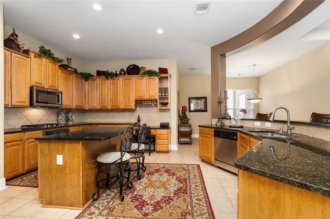 A chef's dream! With a large island, expansive granite countertops, and an abundance of cabinetry, the kitchen has everything you need to make your culinary dreams come to life! | Image 9