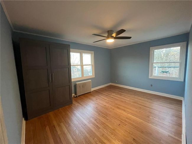 Unfurnished bedroom with light hardwood / wood-style floors, radiator, crown molding, and ceiling fan | Image 6