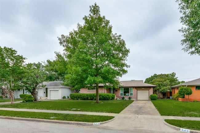 Ranch-style home with a front lawn, concrete driveway, an attached garage, and brick siding | Image 4