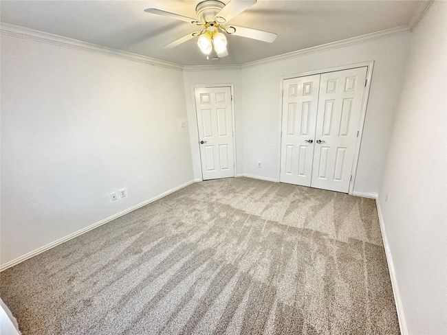 Unfurnished bedroom featuring carpet flooring, crown molding, a closet, and a ceiling fan | Image 27