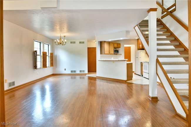 Unfurnished living room featuring wood finished floors, stairs, and a chandelier | Image 5