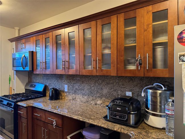 Kitchen with decorative backsplash, dark stone countertops, and appliances with stainless steel finishes | Image 10