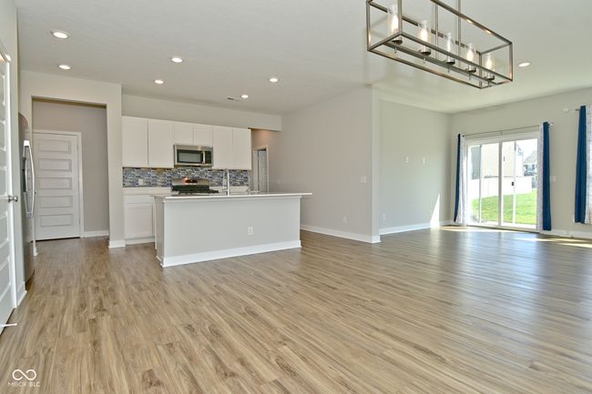 interior space with tasteful backsplash, open floor plan, white cabinets, and stainless steel appliances | Image 6