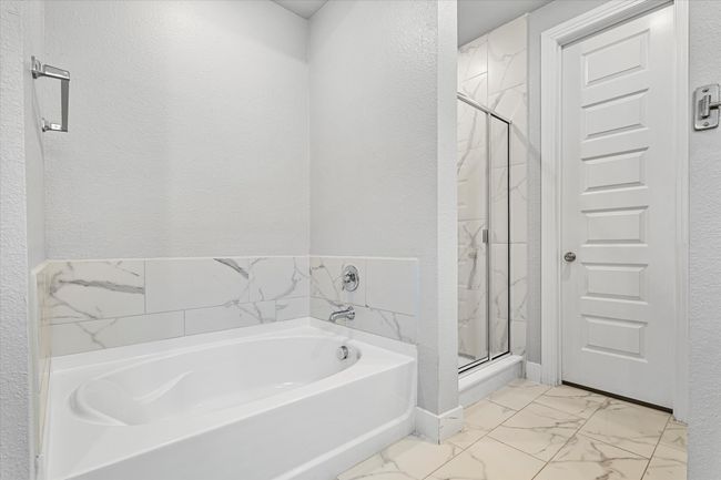 Bathroom with a garden tub, marble finish floor, a textured wall, and a shower stall | Image 13