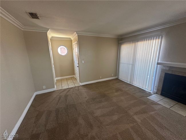 Unfurnished living room with carpet flooring, visible vents, ornamental molding, and plenty of natural light | Image 22