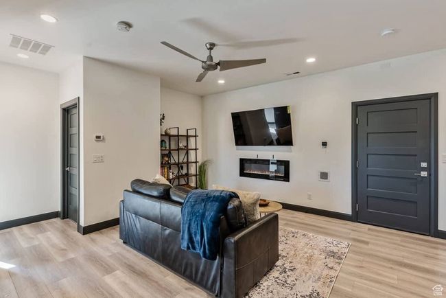 Living area featuring light wood finished floors, a glass covered fireplace, visible vents, and baseboards | Image 29
