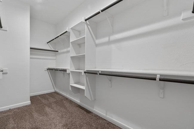 Walk in closet featuring dark colored carpet | Image 15
