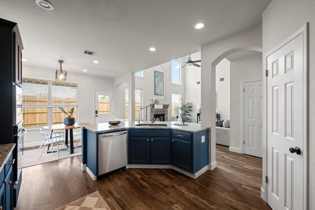Kitchen with stainless steel dishwasher, open floor plan, a sink, a fireplace, and dark wood finished floors | Image 8