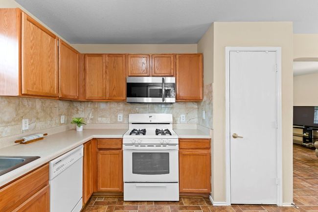 Kitchen featuring white appliances, light countertops, and decorative backsplash | Image 18