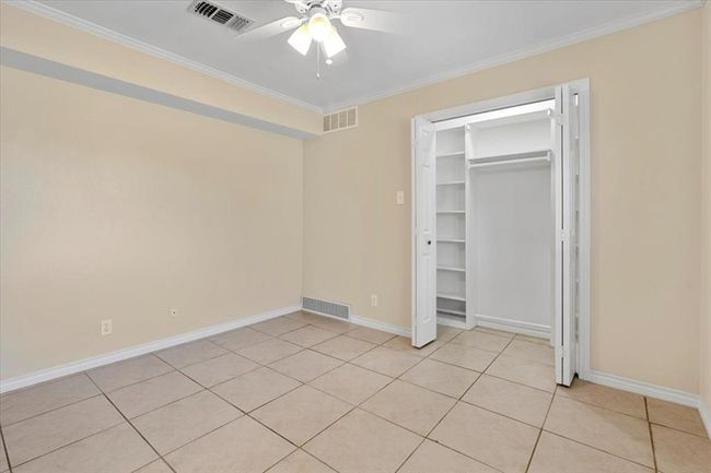 Unfurnished bedroom featuring a closet, ceiling fan, ornamental molding, and light tile patterned floors | Image 22