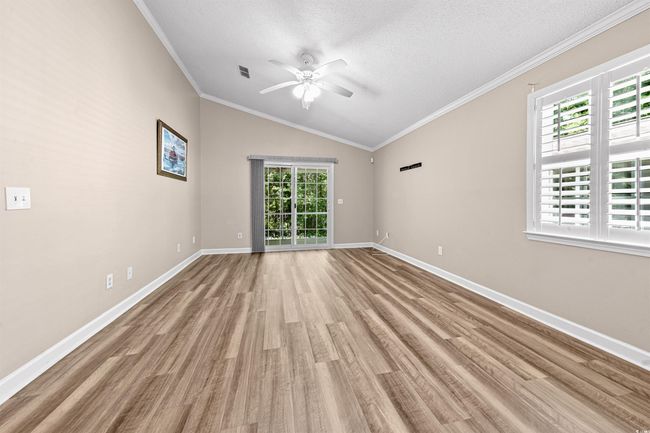 Empty room featuring ceiling fan, wood finished floors, vaulted ceiling, and a healthy amount of sunlight | Image 16