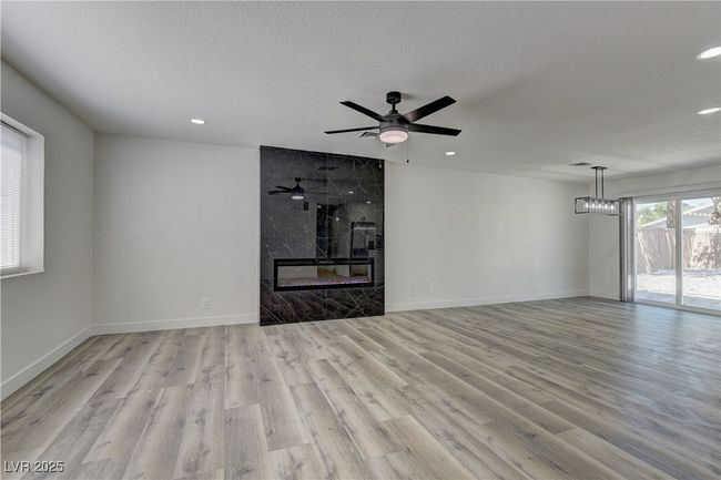 Unfurnished living room with wood finished floors, recessed lighting, baseboards, a premium fireplace, and a ceiling fan | Image 6