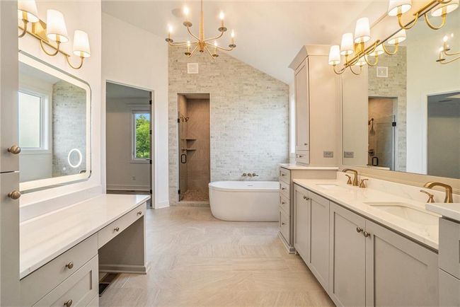 Full bath featuring a chandelier, lofted ceiling, a shower stall, double vanity, and a freestanding tub | Image 42