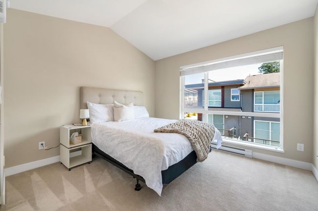 Carpeted bedroom with baseboards, lofted ceiling, and a baseboard radiator | Image 12