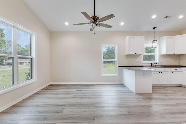 Kitchen featuring dark countertops, a sink, light wood-style floors, white cabinets, and recessed lighting | Image 6