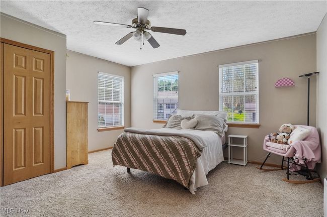 Bedroom with a textured ceiling, a ceiling fan, baseboards, and light carpet | Image 32